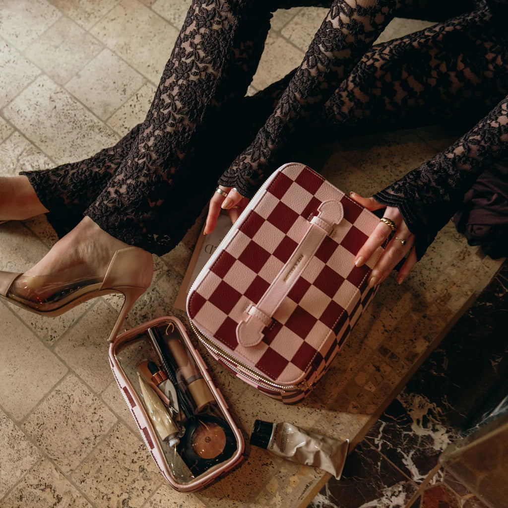 Person holding a checkered makeup case on a marble surface