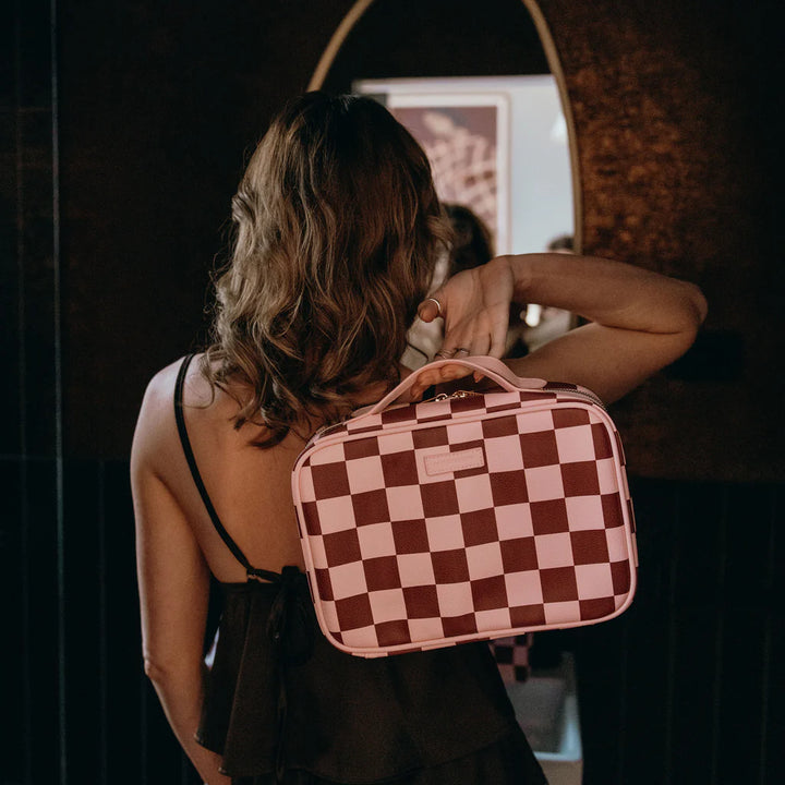 Woman holding a checkered bag in front of a mirror