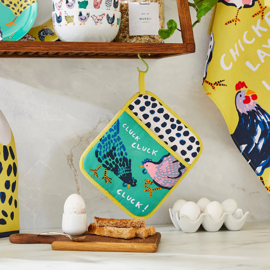 Colorful kitchen towel with chicken design hanging on a shelf with other kitchen items.