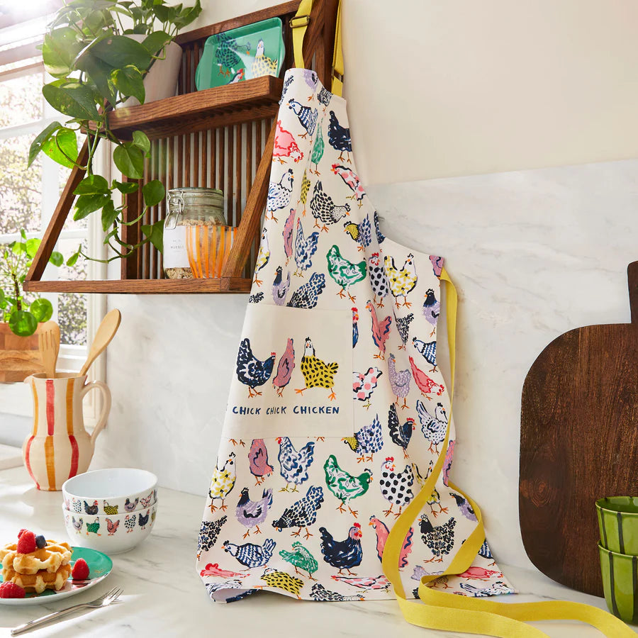 Colorful apron with chicken pattern hanging on a hook in a kitchen.