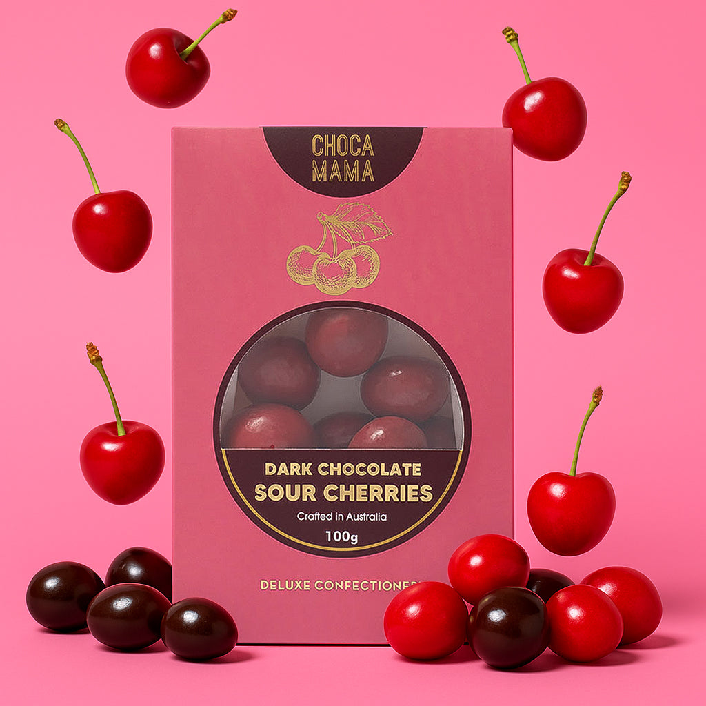 Box of Choca Mama dark chocolate sour cherries on a pink background with scattered cherries around.