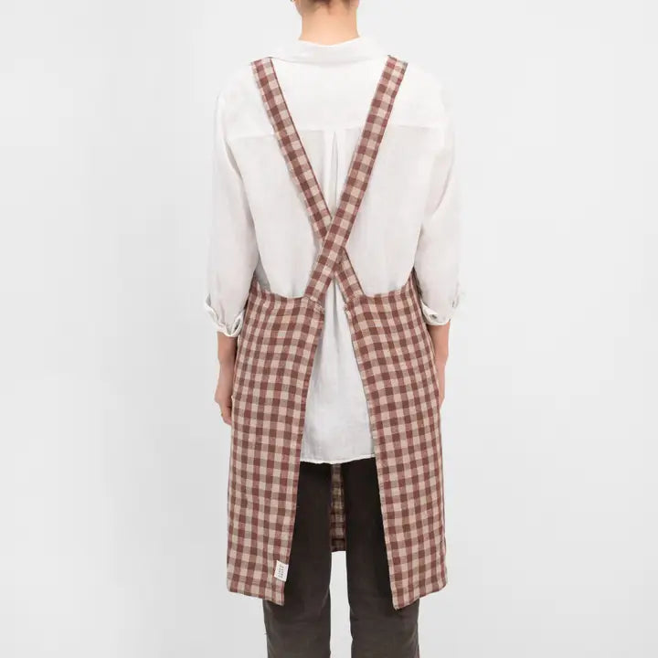 Person wearing a plaid apron over a white shirt on a light gray background