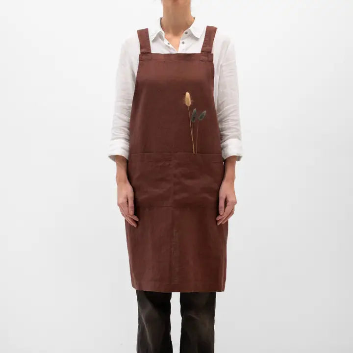 Person wearing a brown apron with floral design on a white background