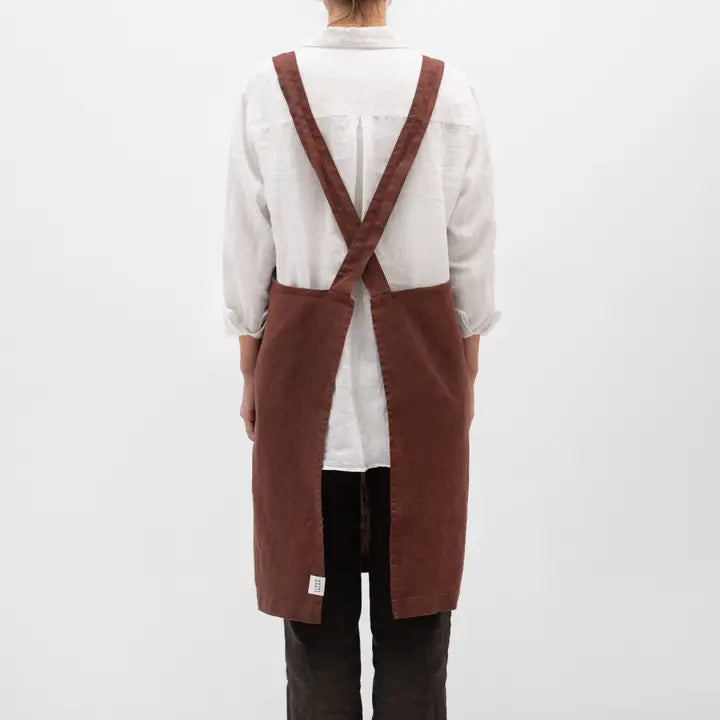 Person wearing a brown apron over a white shirt on a white background