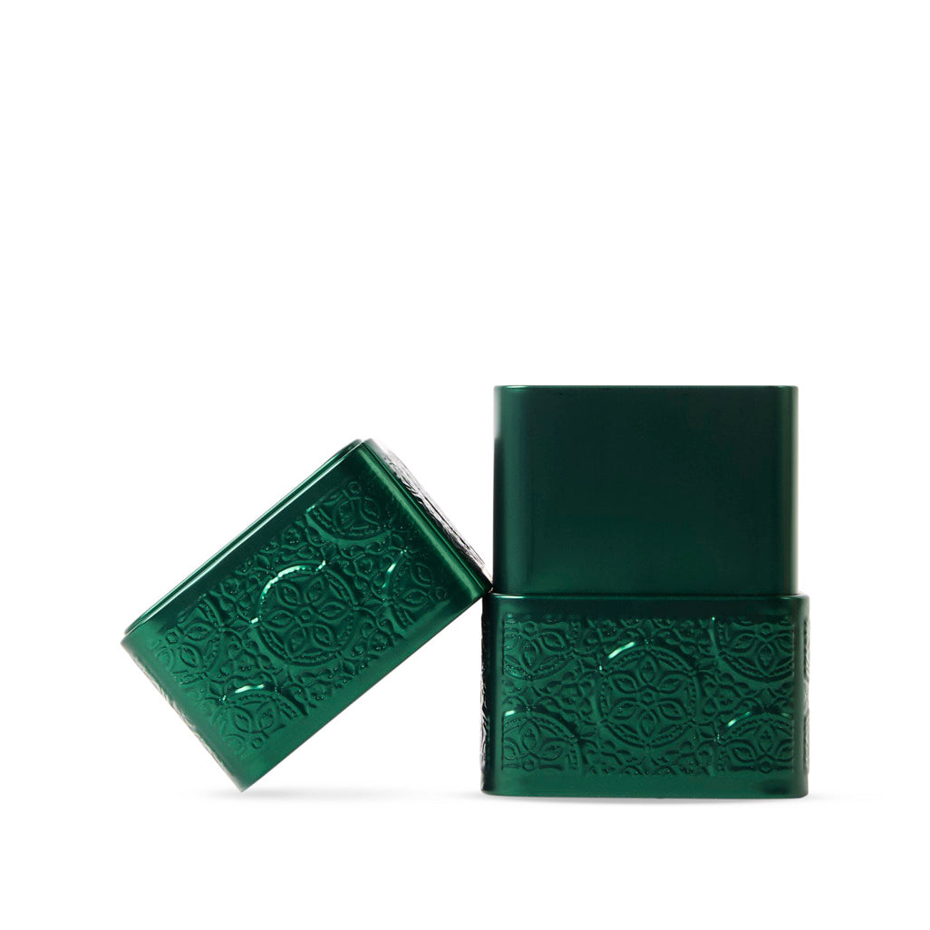 Two green playing card boxes with embossed designs on a white background