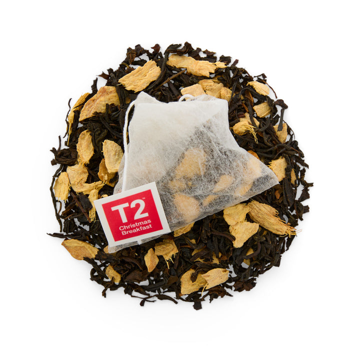 Tea bag with T2 Christmas Breakfast label on a bed of black and yellow tea leaves.