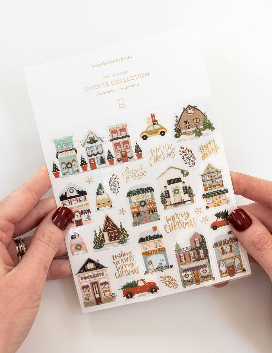 Sticker collection with Christmas-themed designs held by hands on a white background