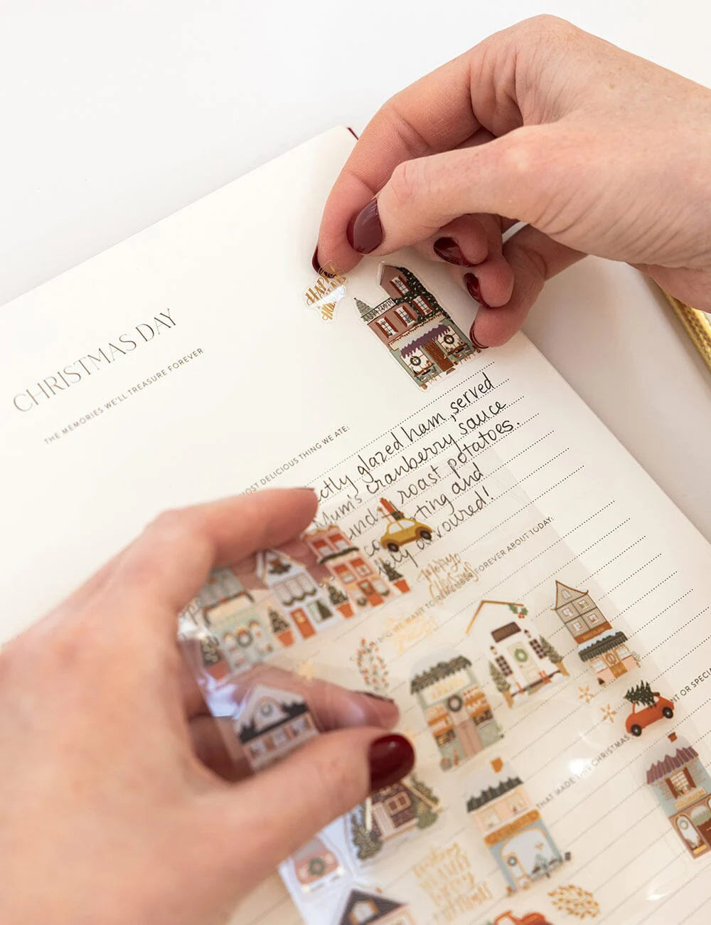 Person applying Christmas-themed stickers to a notebook page.