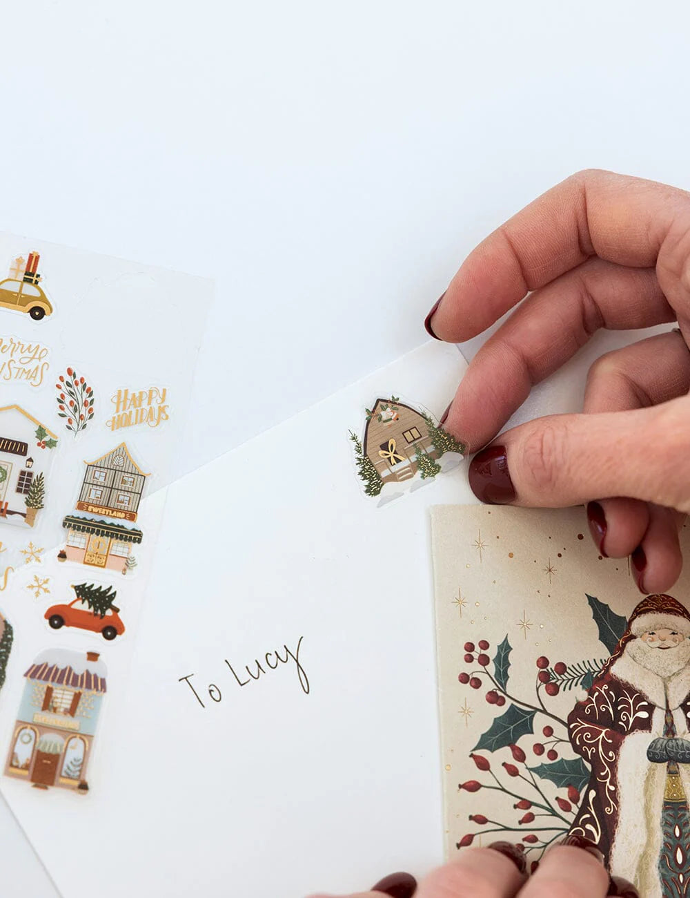 Hand holding a Christmas-themed card with decorative elements on a white background