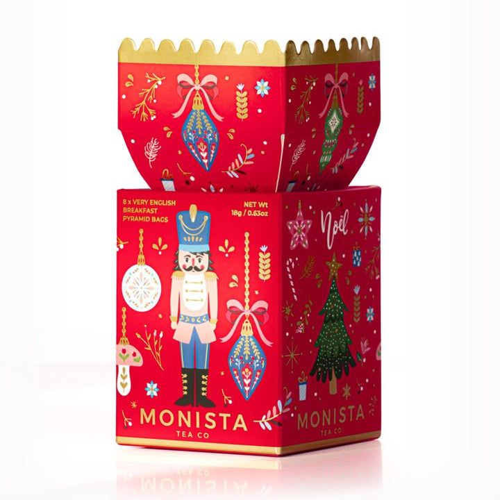 Decorative red tea boxes with festive designs and 'Monista Tea Co' branding on a white background.