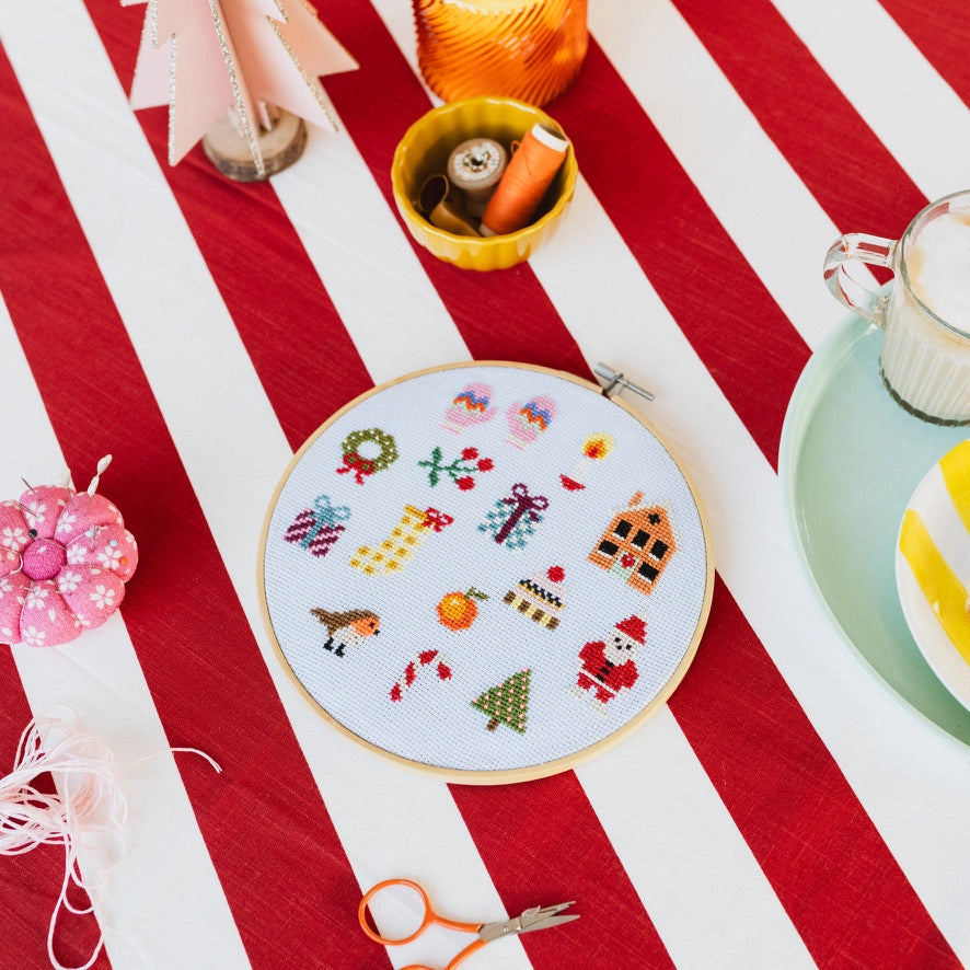 Embroidery hoop with colorful patterns on a red and white striped fabric background.