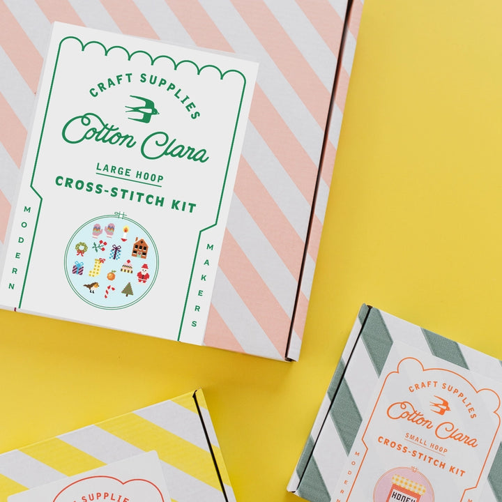 Cotton Clara cross-stitch kit packaging on a yellow and pink striped background