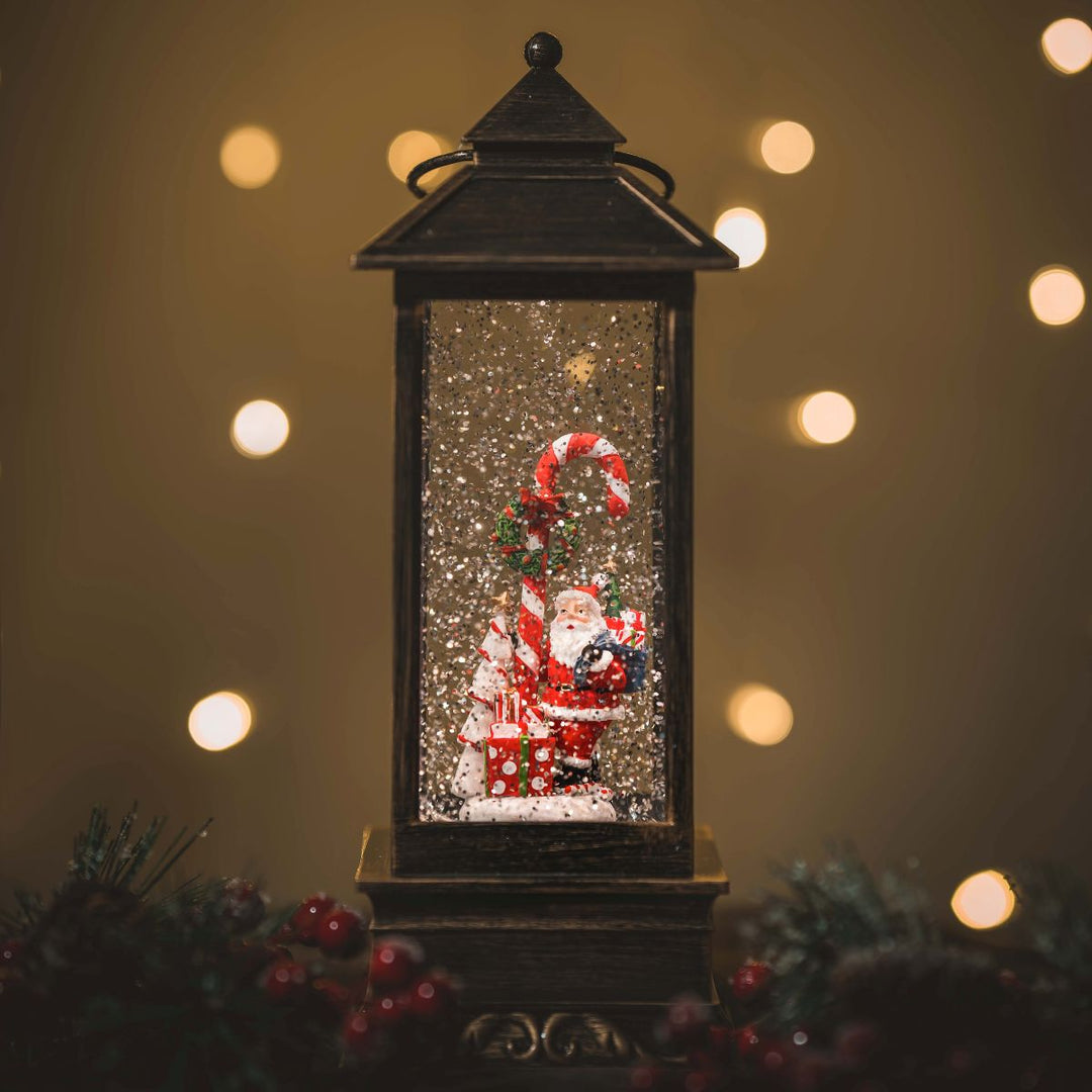 Decorative lantern with Santa Claus figure and candy cane against a warm, blurred light background