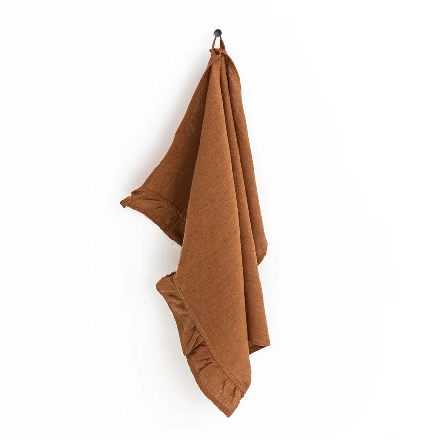 Brown tea towel hanging on a hook against a white background