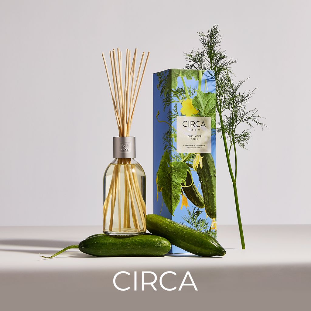 Circa diffuser bottle with reeds, packaging, and cucumbers on a light background