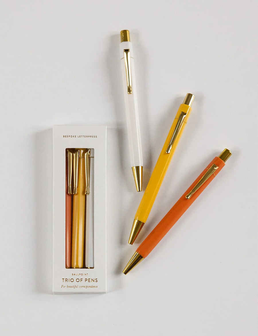 Three pens with gold accents and a packaging box on a light gray background