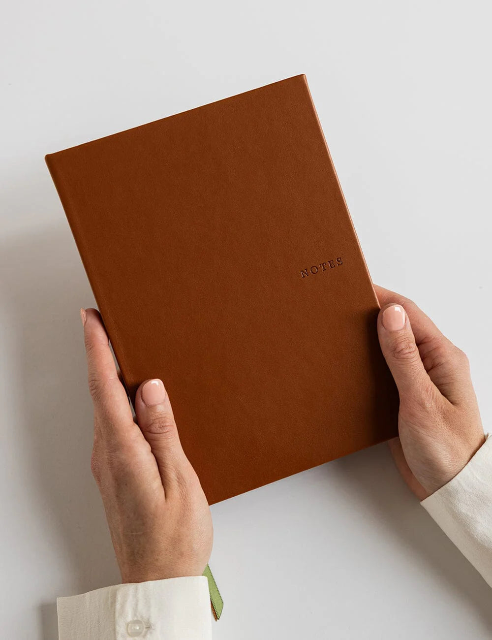 Brown notebook held by hands on a light background