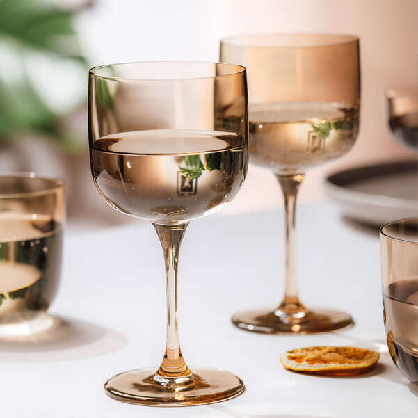 Amber coloured wine glasses on a white surface with a blurred background