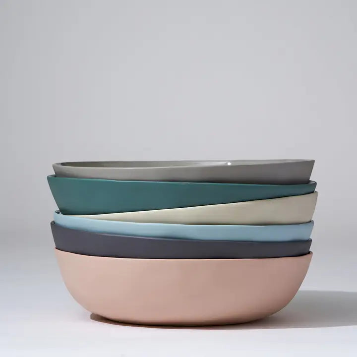Stack of colorful ceramic bowls on a light gray background