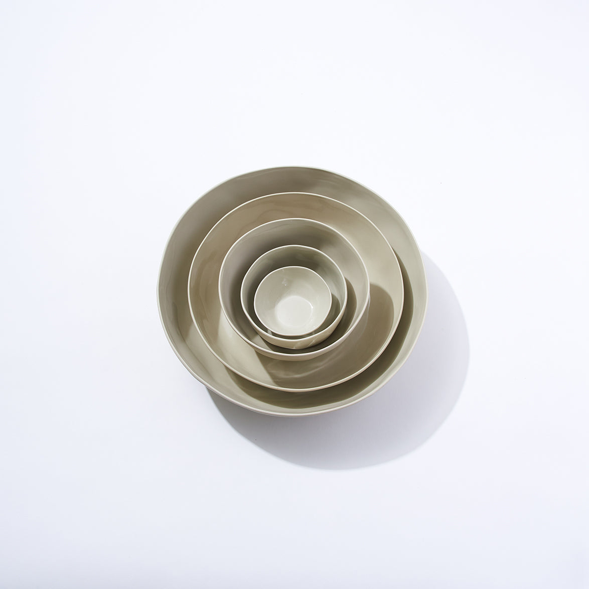 Set of five beige ceramic bowls of different sizes on a white background