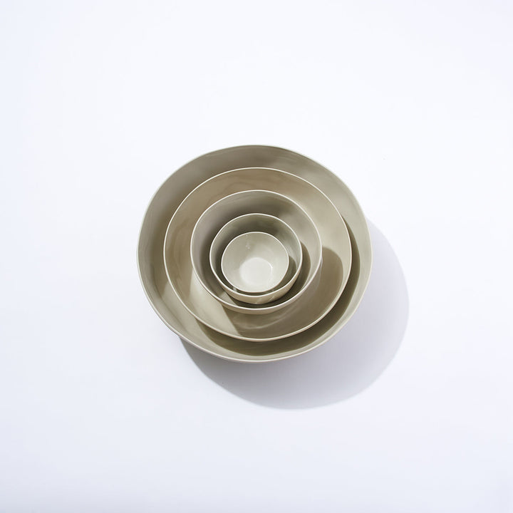 Set of five beige ceramic bowls of different sizes on a white background