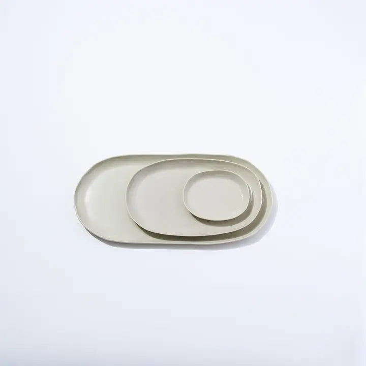 Set of three beige ceramic trays on a light gray background