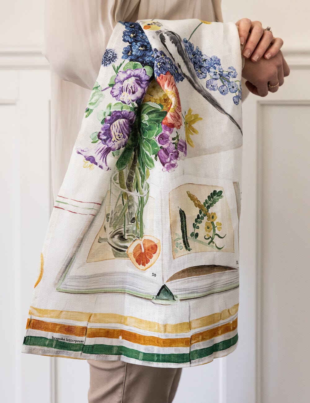 Linen tea towel with flowers a cockatiel on it over someones arm