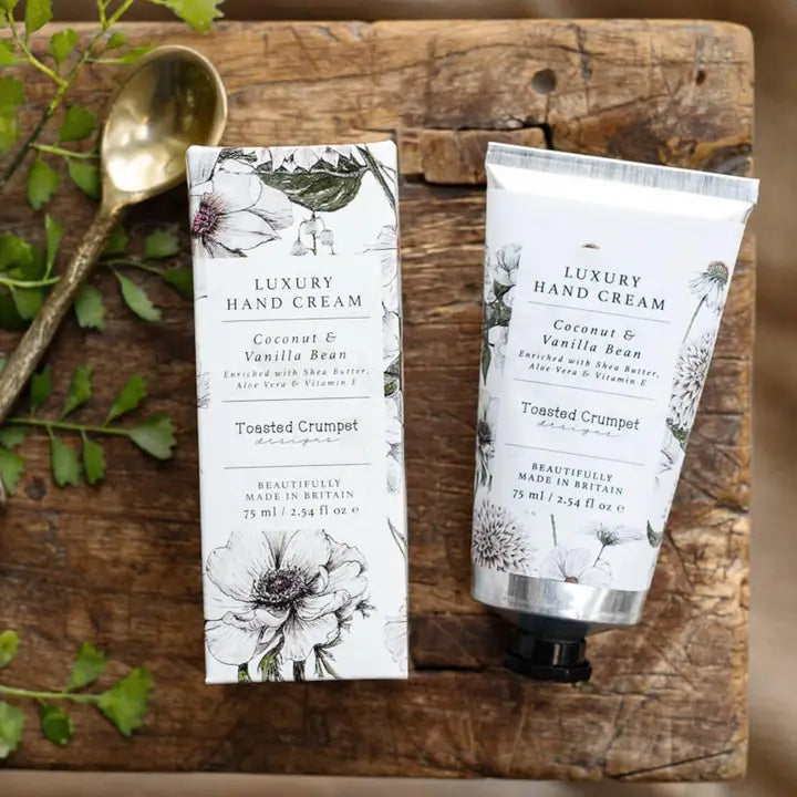 Luxury hand cream packaging on a wooden surface with a spoon and leaves.