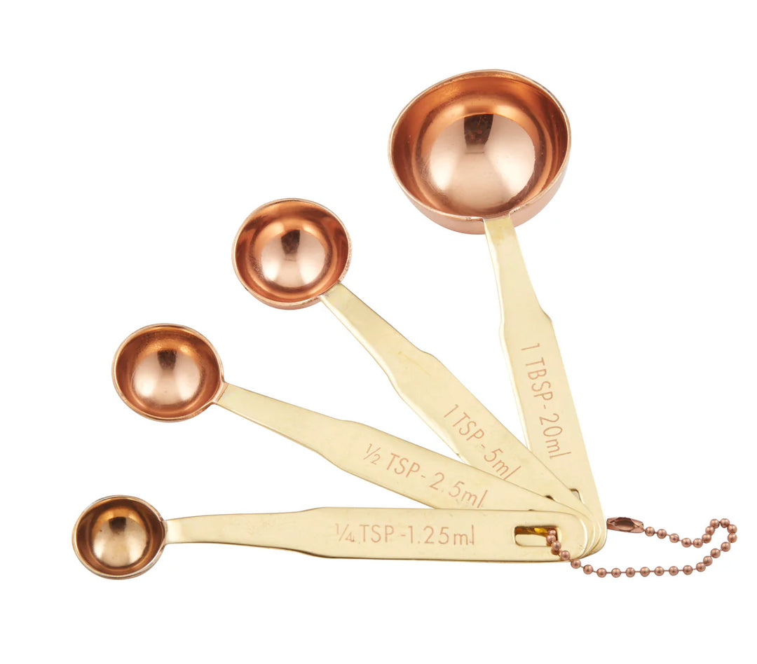 Set of copper measuring spoons with gold handles on a white background