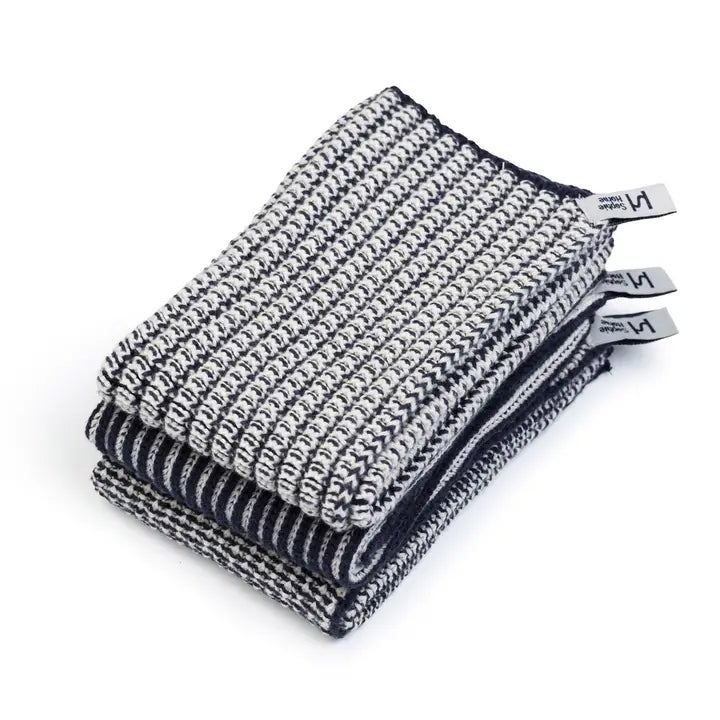 Stack of blue and white textured dish towels with brand tags on a white background