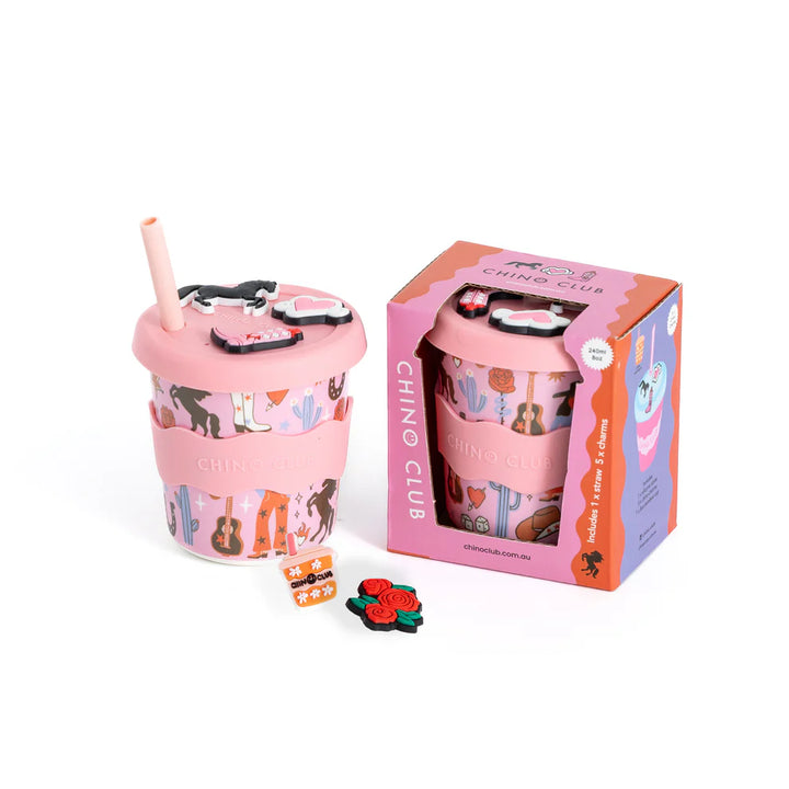Pink cup with straw and decorative elements next to its packaging on a white background