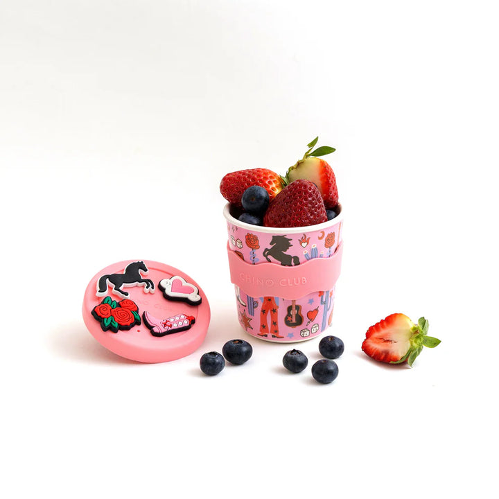 Pink cup with horse design filled with berries on a white background
