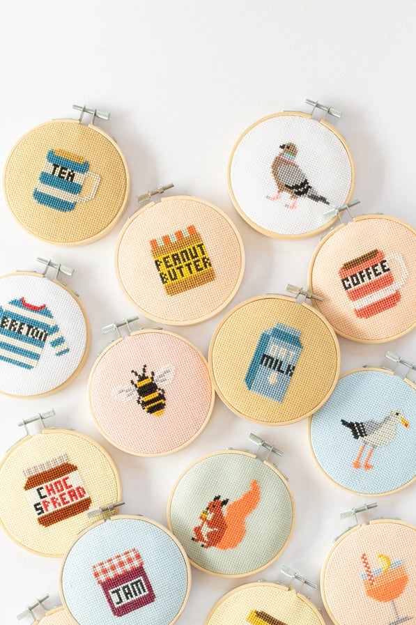 Collection of cross-stitched hoops with various designs on a white background