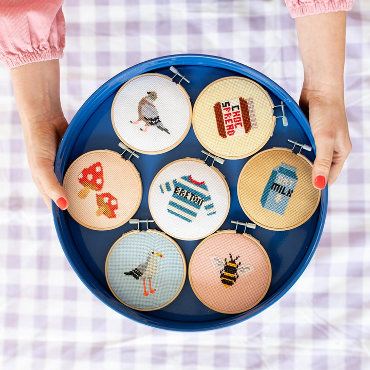 Set of embroidered hoops with various designs held in a blue tray.