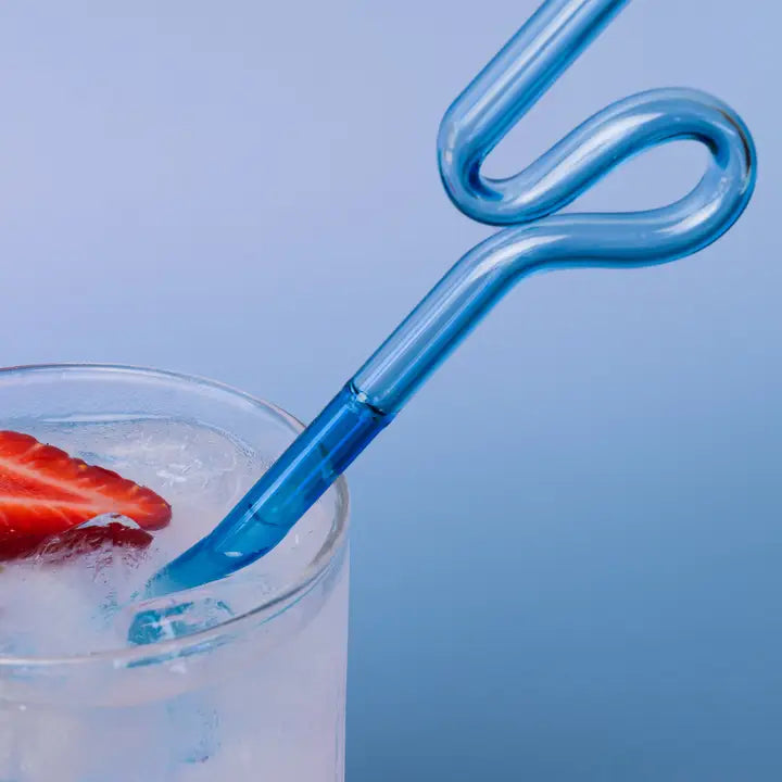 A curly blue glass straw in a glass on a blue background