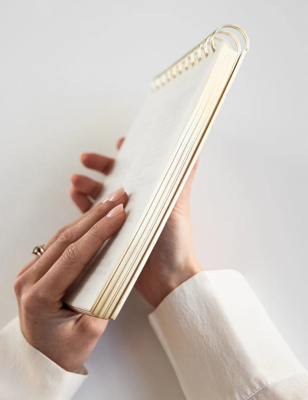 Hand holding a spiral-bound notebook on a light background