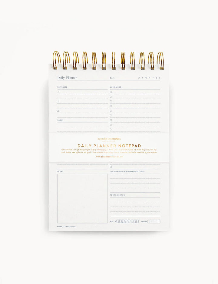 Daily planner notepad with gold accents on a white background