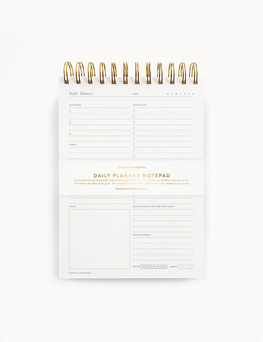 Daily planner notepad with gold accents on a white background