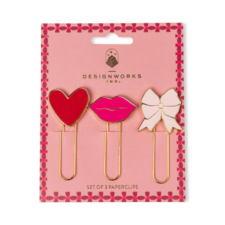 Set of three paperclips shaped like a heart, lips, and a bow on pink packaging with &
