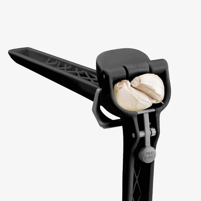 Black garlic peeler with two cloves of garlic on a white background