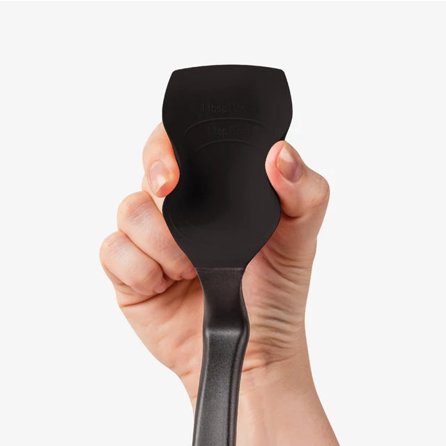 Hand holding a black spatula against a white background