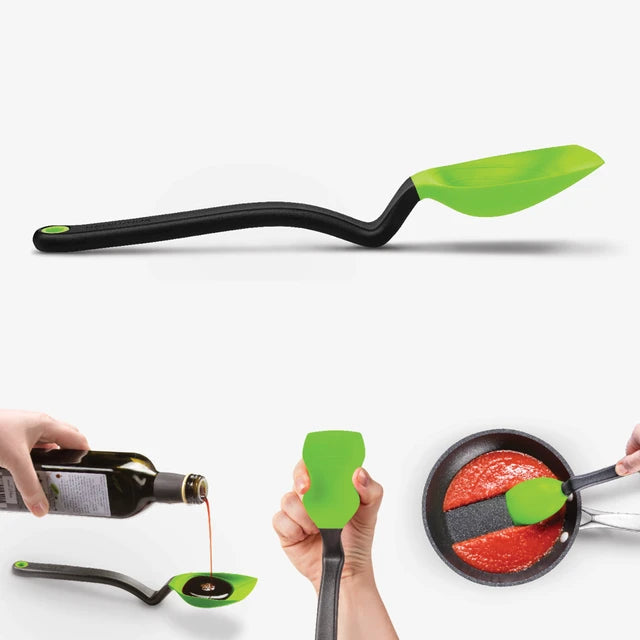 Flexible spatula with green head and black handle being used to pour oil and spread sauce on a pan.