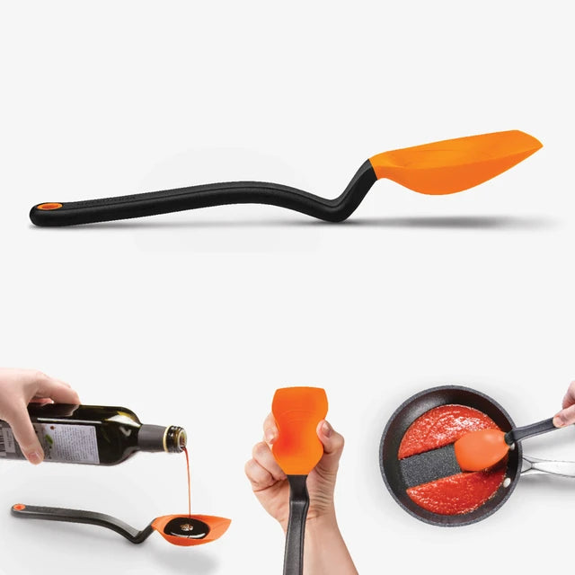 Spatula with orange head and black handle being used to pour oil and mix sauce in a pan on a white background