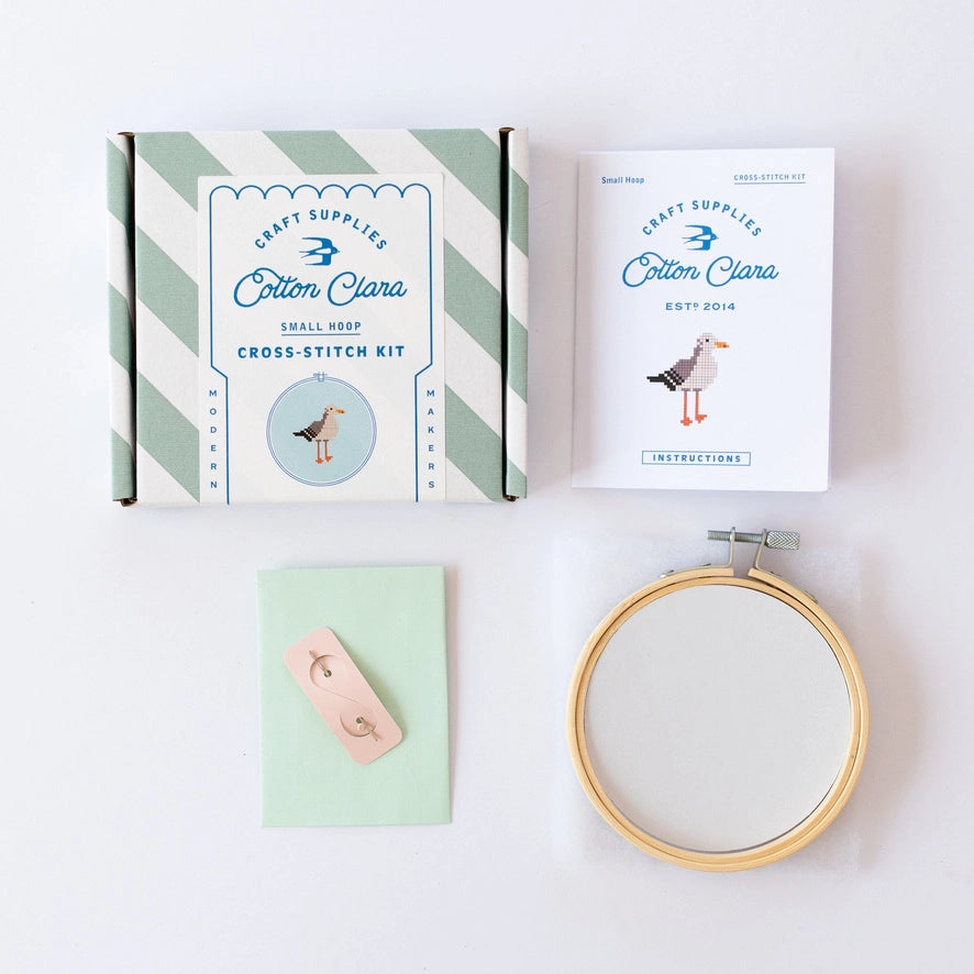 Cotton Clara cross-stitch kit with hoop, thread, and needle on a white background
