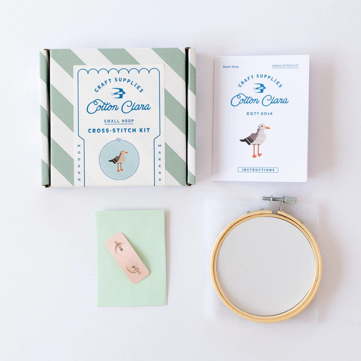 Cotton Clara cross-stitch kit with hoop, thread, and needle on a white background