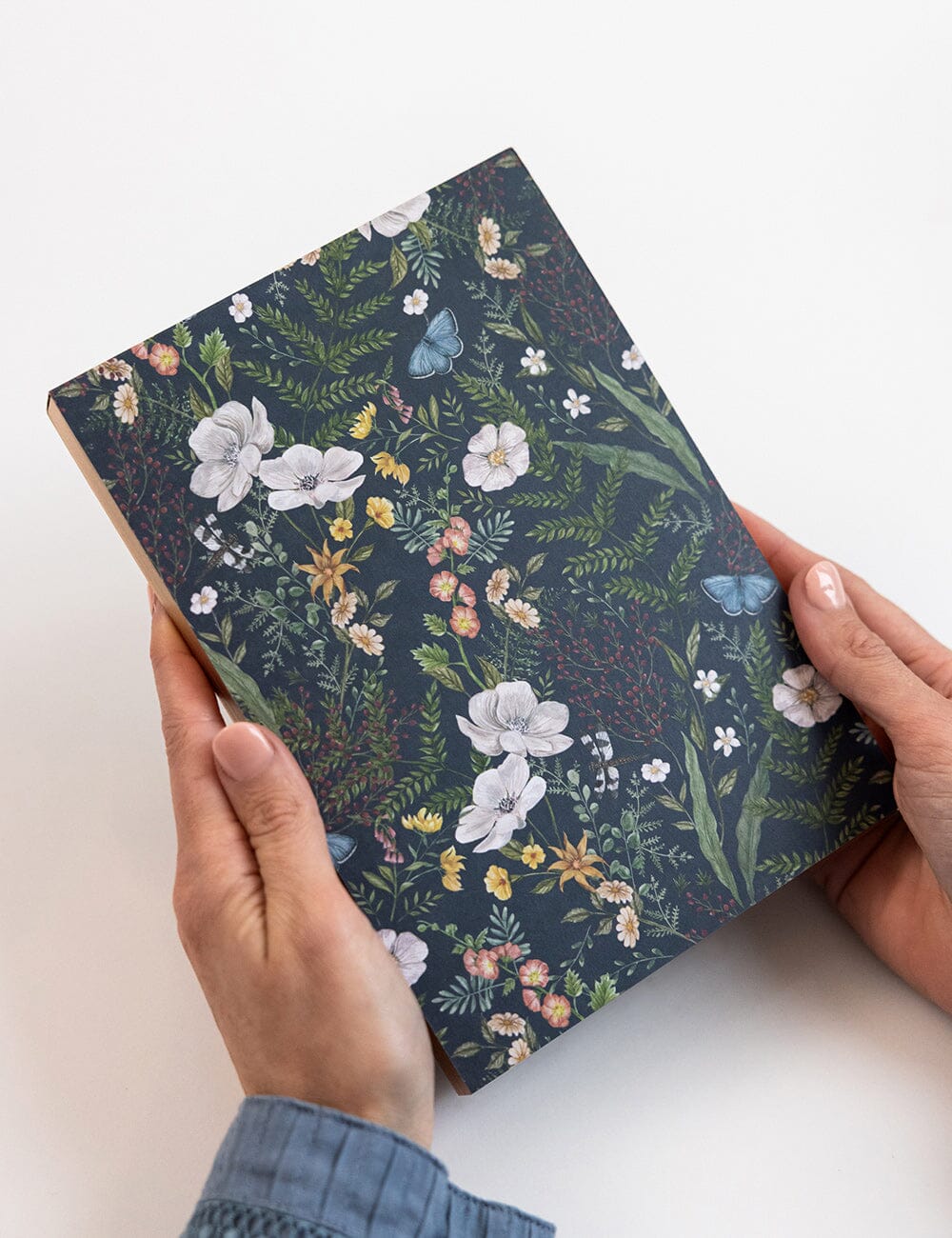 Floral-patterned notebook held by hands on a white background