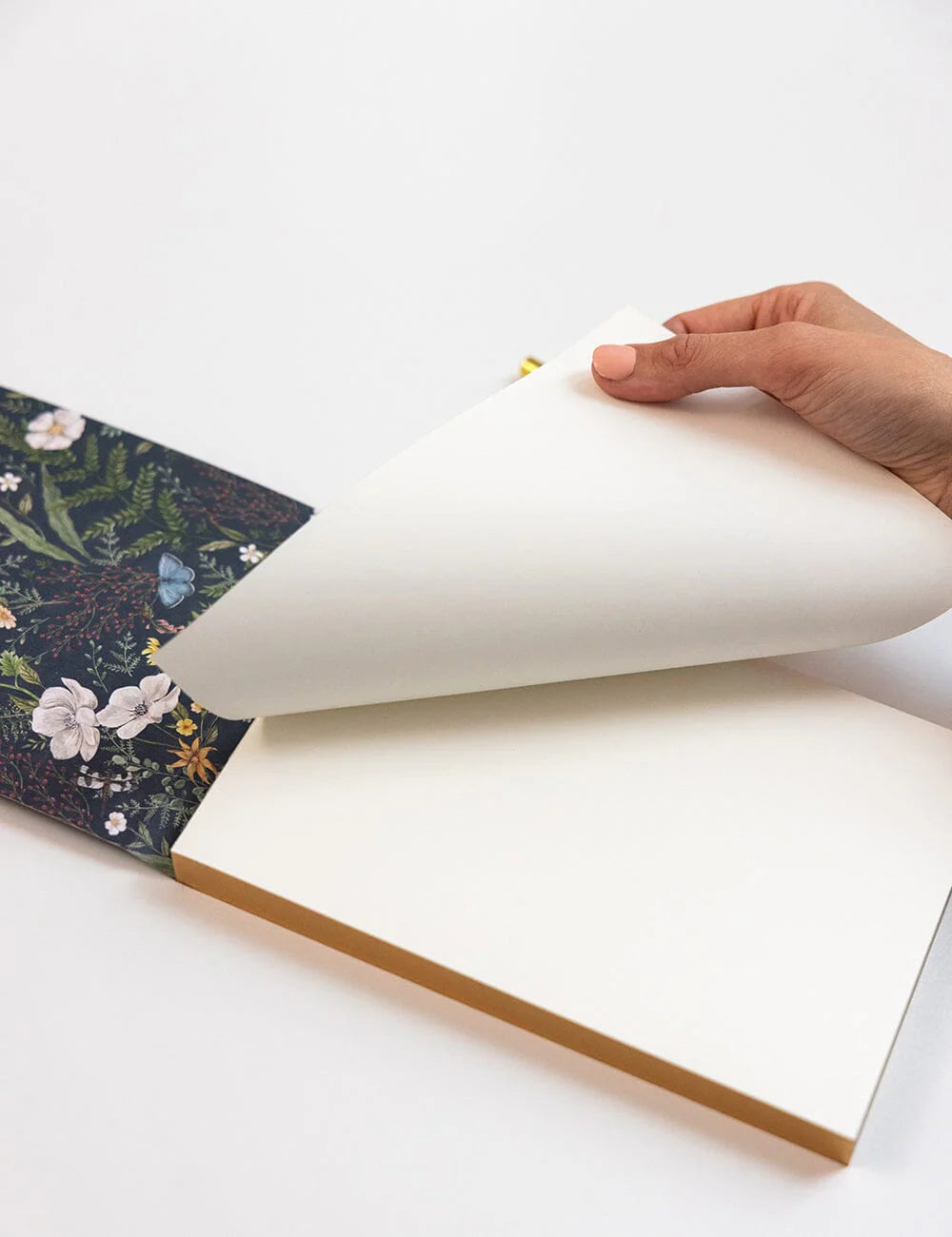 Hand opening a notebook with floral design on the cover
