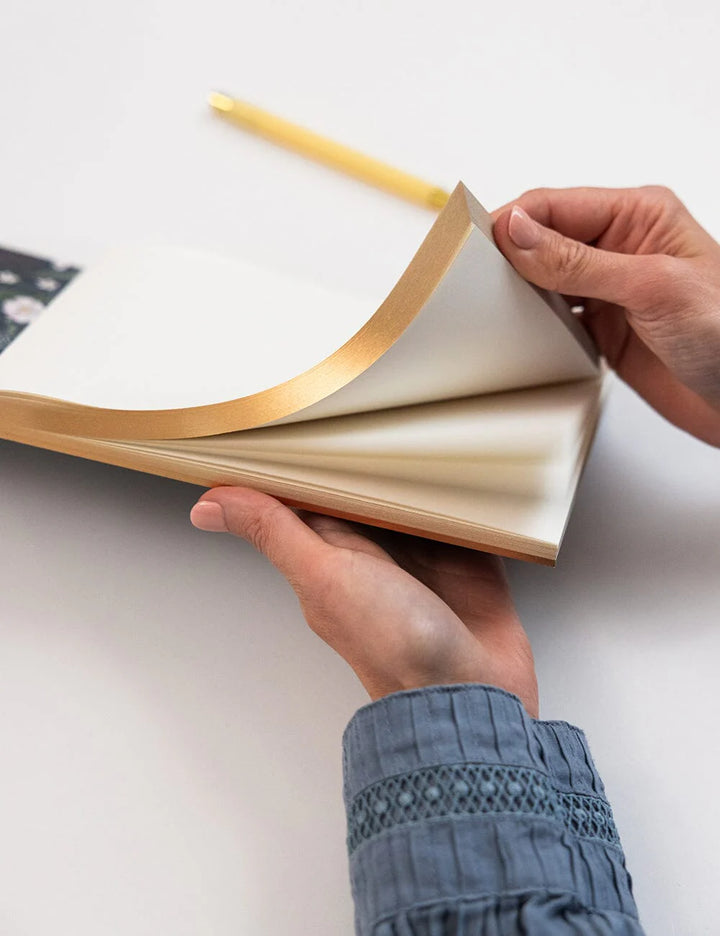Person holding a book with gold edges on a white background