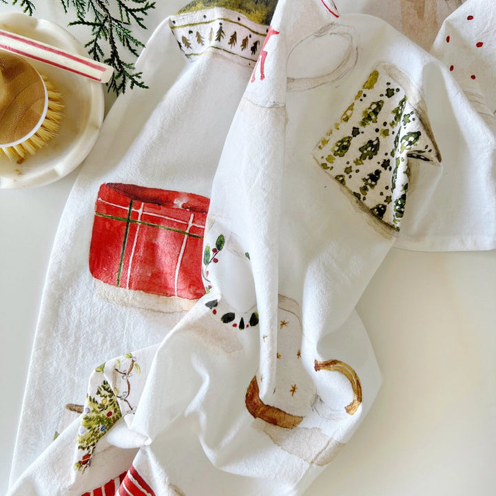 Decorative kitchen towels with festive designs on a white surface.