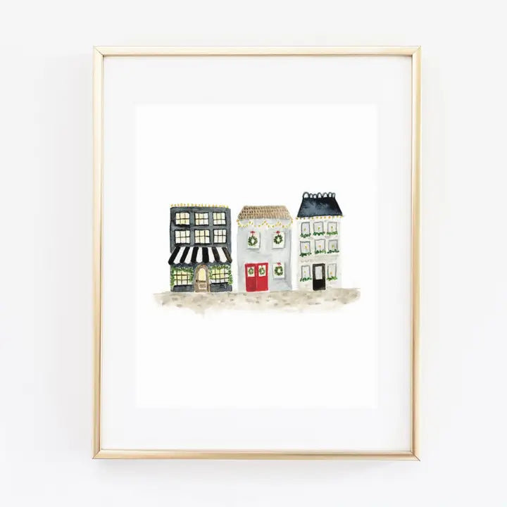 Watercolour print art work of Christmas village in a brass frame on a white background
